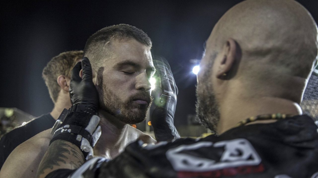 Amateur MMA fighter checked by a ringside doctor inside the octagon after his victory at an outdoor fight night