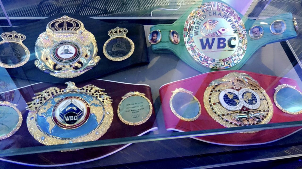 WBA, WBC, IBF and WBO world title belts held by Oleksandr Usyk displayed on a table