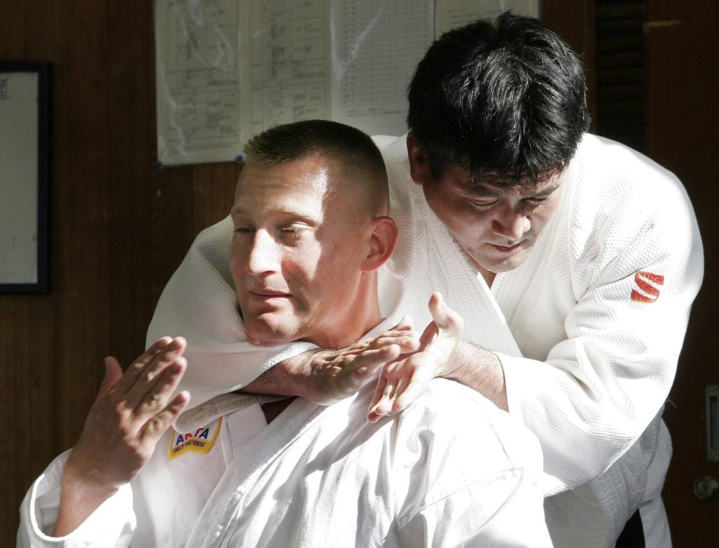 Instructor applying a rear choke to a training partner on a mat