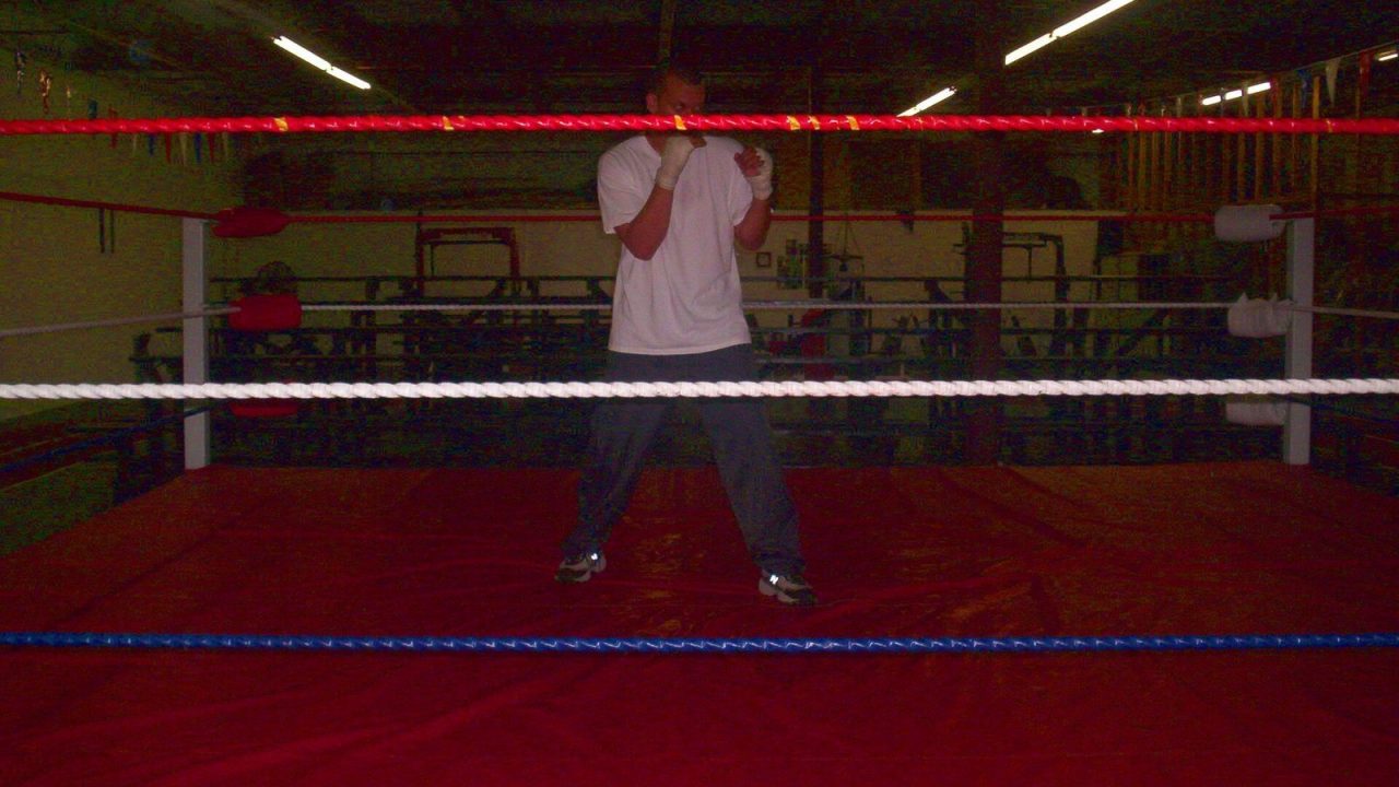 Boxer standing in a boxing stance in a gym with hands up